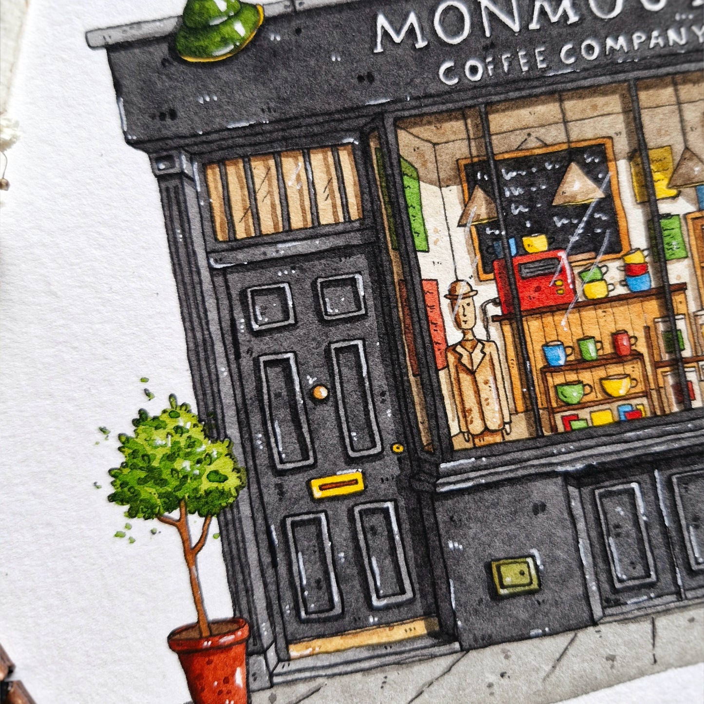 Watercolor and ink painting by inky paper house of a coffee shop named 'Monmouth Coffee Company' with a potted plant in the foreground.