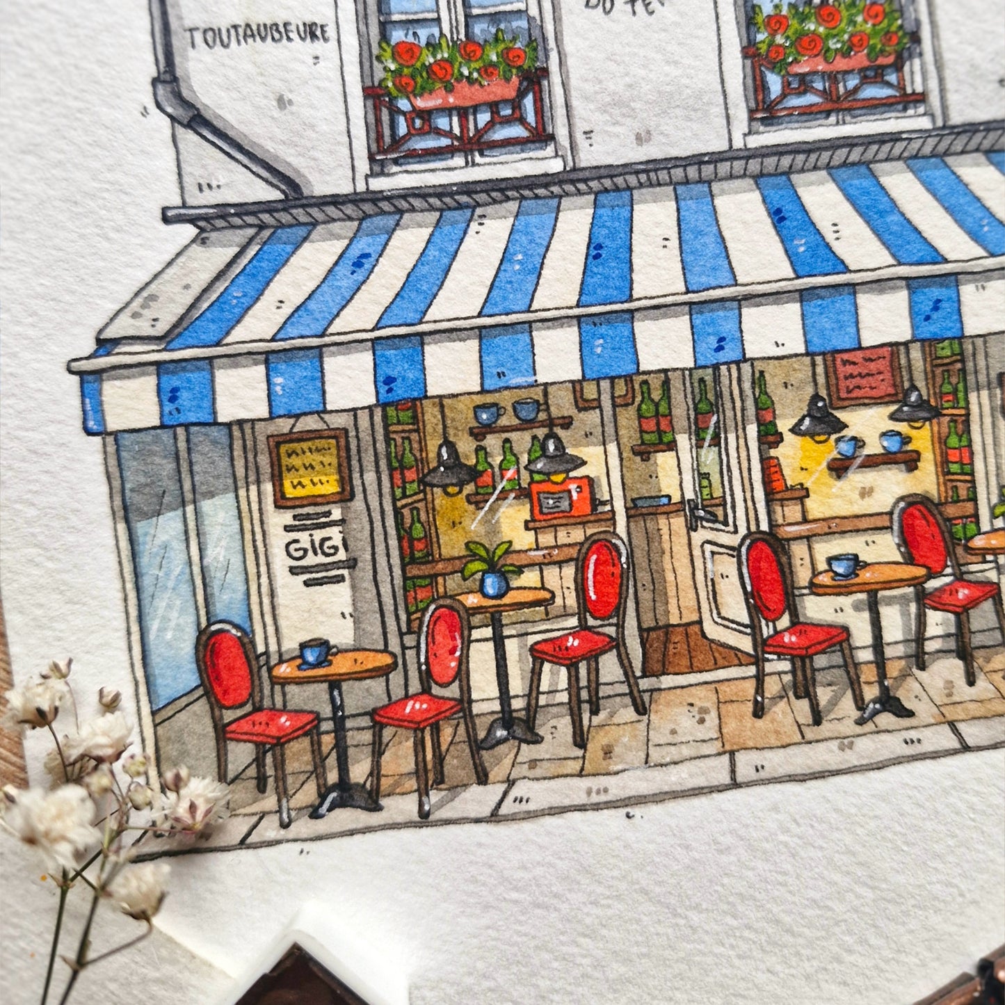 watercolor and ink Illustration of a cozy café with red chairs and a blue and white striped awning.